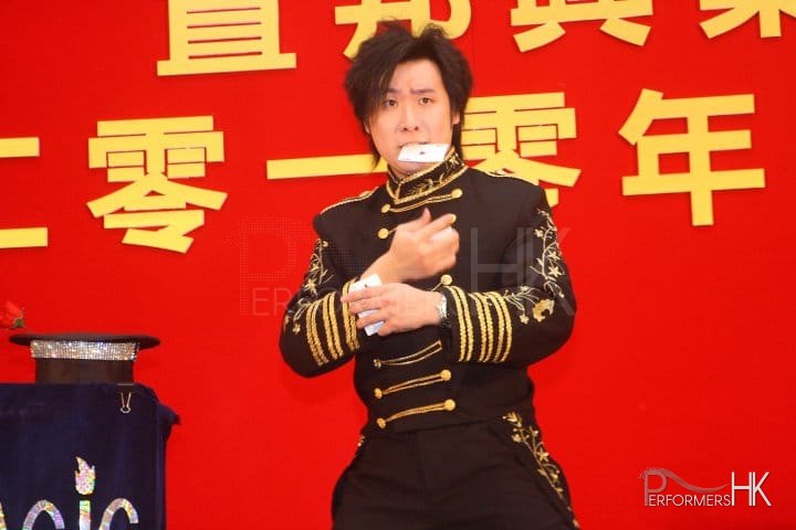 Magician performing stage magic with card nest to the magic hat at a annual dinner