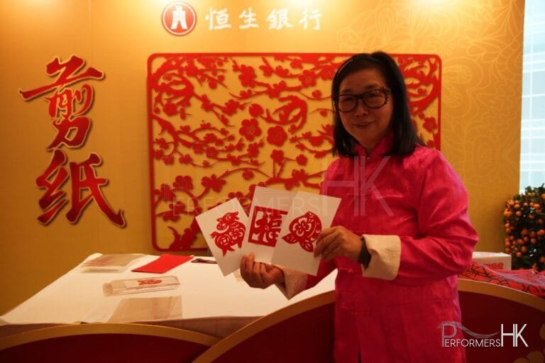 chinese artist cutting zodiac handicraft wearing red at Hang Seng bank in Hong Kong
