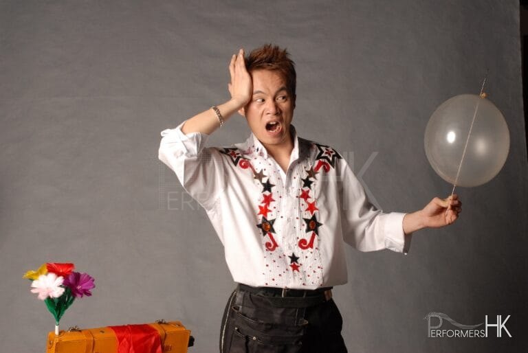 HK Magician performing a needle through balloon magic trick for kids next to magic flowers