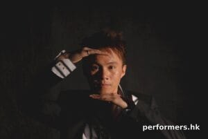 Hong Kong Magician head shot holding his hands in front of his forehead and chin