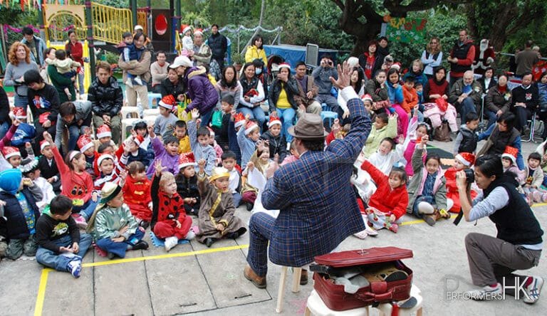Performer in HK putting his right hand up to the air and the audience is coping him at a corporate family event