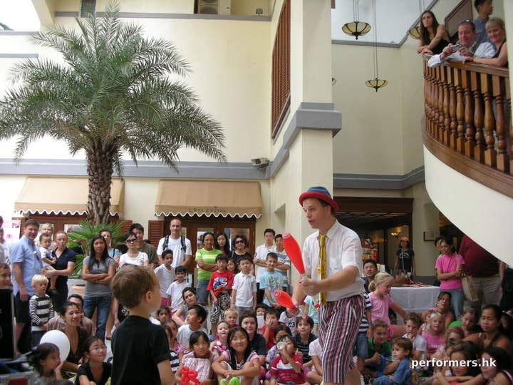 Performer doing a juggling trick in front of kids audiance
