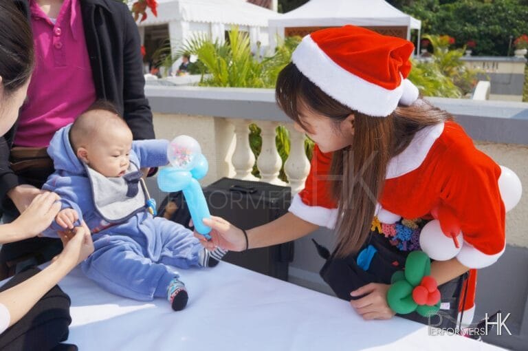child being passed a balloon by balloon twister genie in red costume at 109 repulse bay hong kong christmas time