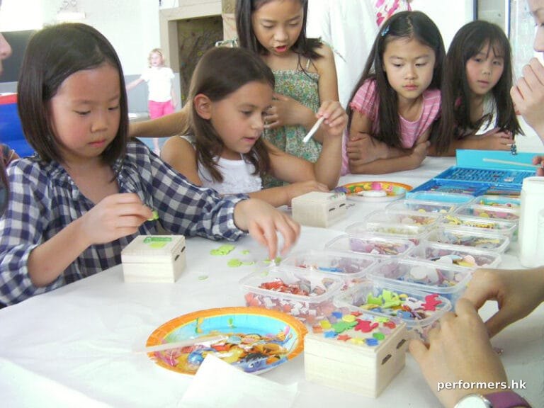 Five girls is choosing different materials  to decorate their own jewelry box at a corporate kids event