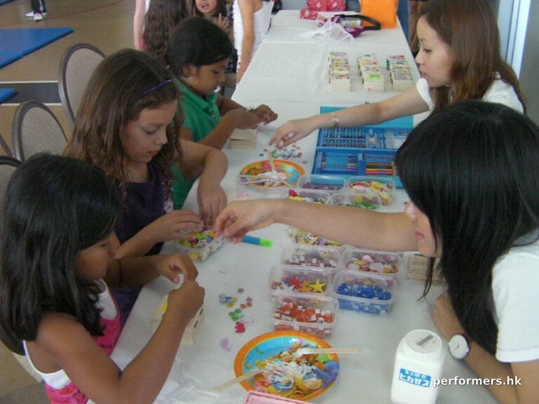 Two staff is assisting the children to decorate their own crafts at a corporate event