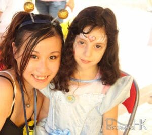 Face painter posing with child wearing princess makeup