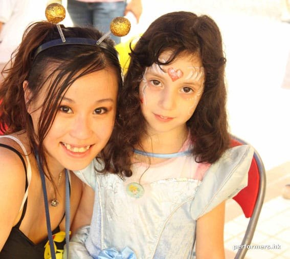 Face painter posing with child wearing princess makeup