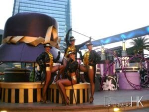 4 dancers in front of giant hat prop at a mall in Hong Kong