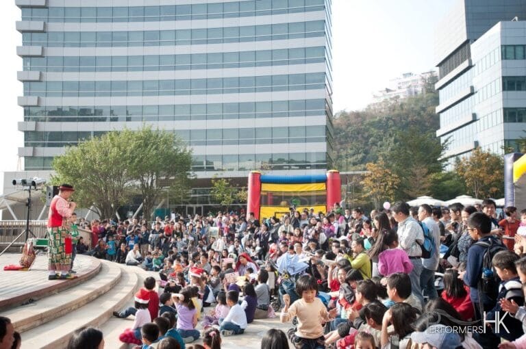Performers on Cyberport podium for a clown  show being watched by a huge crowd