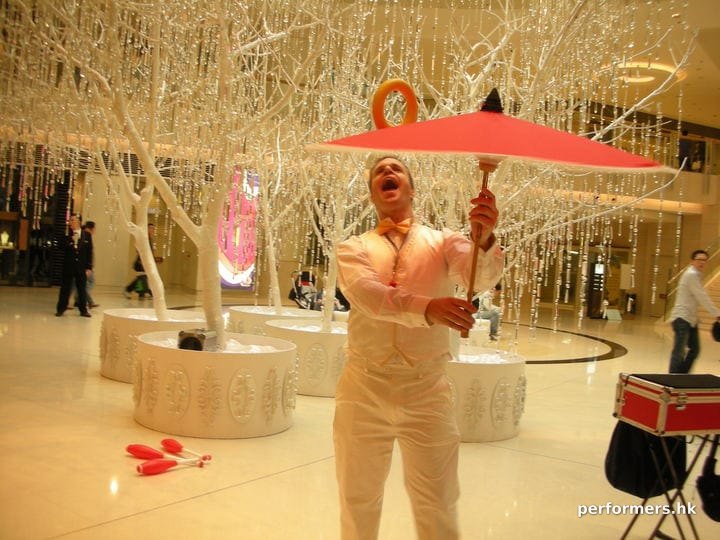 Juggler wearing white , juggling with umbrella and ring at a Hong Kong Christmas corporate event