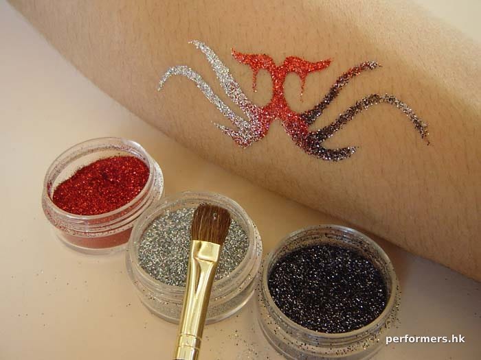 A glittering tattoo with red , sliver and black glitter by artist at a corporate event.