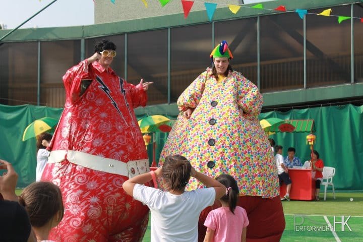 Two inflatable stilts walkers dressed as Elvis and Hawaiian costume roving for a family day in Hong Kong