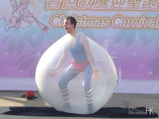 Juggler performing his famous trick , getting inside the giant balloon act at a Hong Kong Christmas Carnival