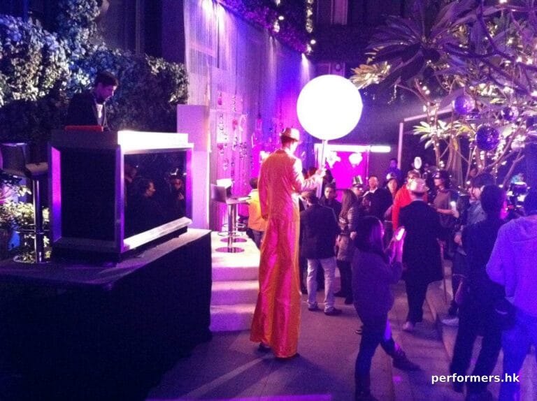 Stilt walker wearing golden costume and holding a giant chupa chup