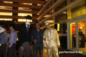 Headless man living statue standing next to a gold man living statue