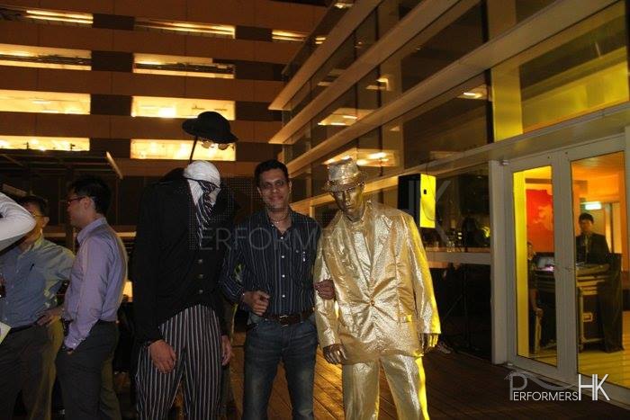 Headless man living statue standing next to a gold man living statue
