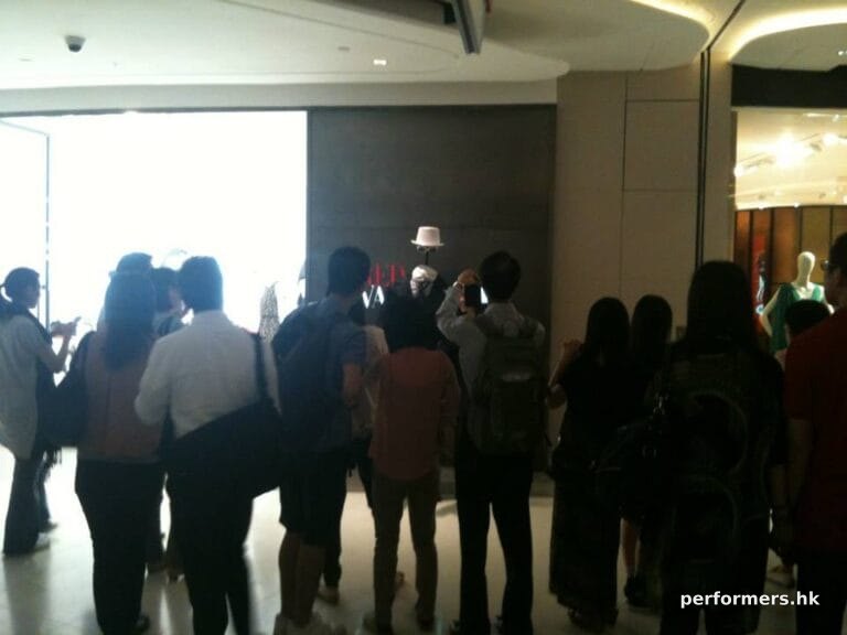 Headless man living state surrounded by large crowd at shopping mall