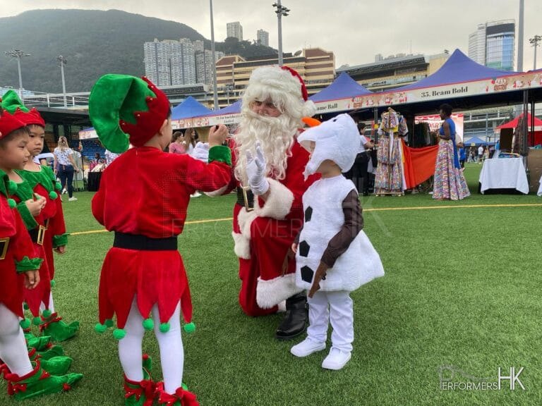 Santa in red costume with child in elf costume and child in snowman costume at sports road, causeway bay hong kong, hong kong football club