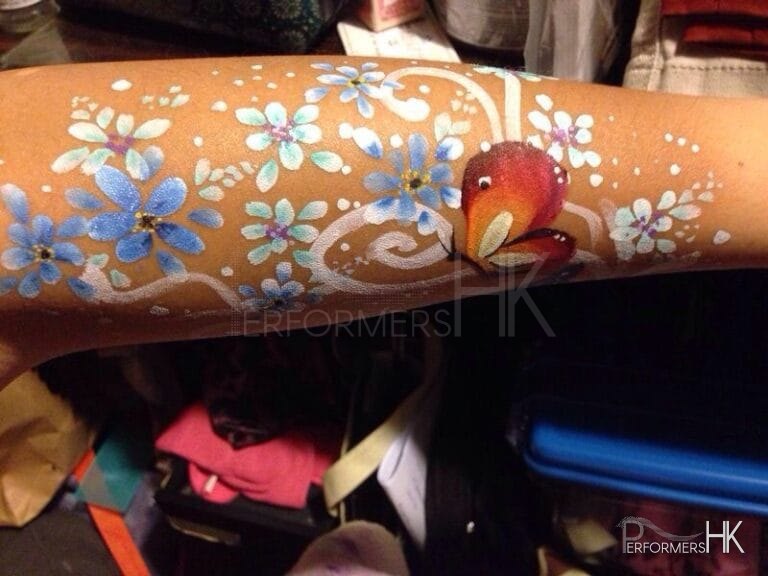 A face painter finished a beautiful flower and butterfly paint on arm at a Hong Kong family fun day event