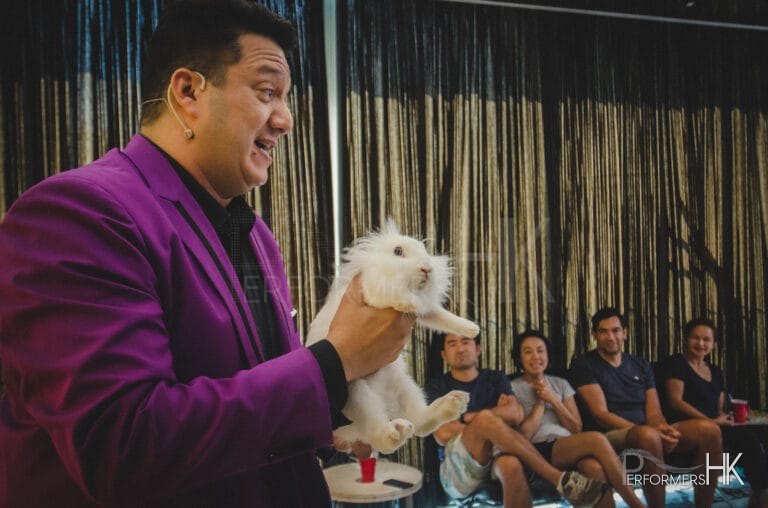Hong Kong Magician in purple suit performing magic with a live bunny at a corporate event