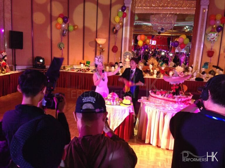 Hong Kong Magician performing roving magic with the birthday lady who holding a bottle of wine at a hat theme adult birthday party