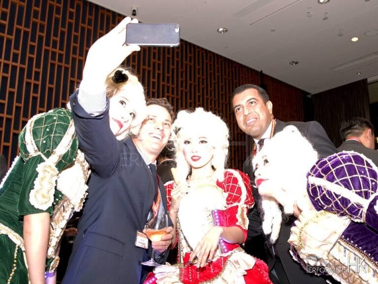 Three performers wearing victorian costume taking picture with guest in a corporate cocktail setting