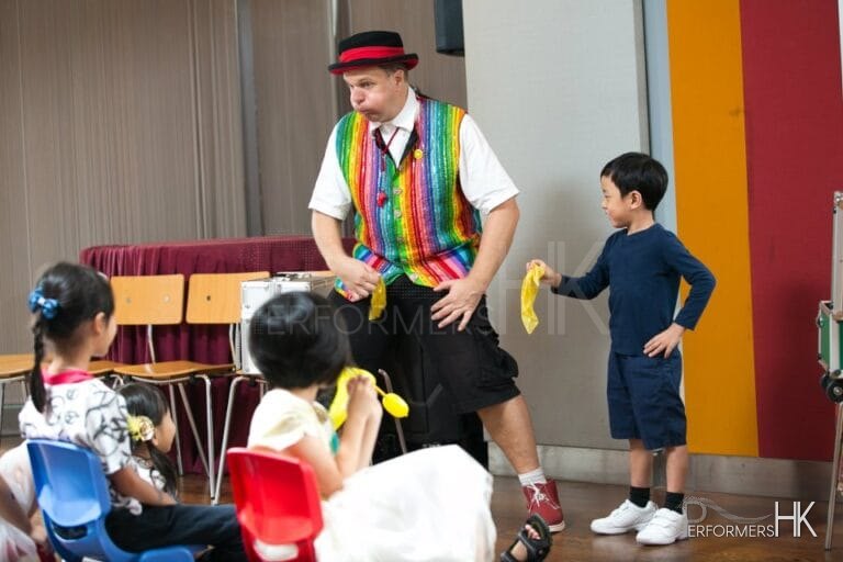 A Clown in Hong Kong invited a little boy audience to perform with him, they shake the yellow silks together and ready to turn it to a different color at a school event