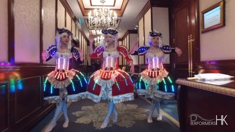 Three dancers wearing victorian era dresses with LED lights