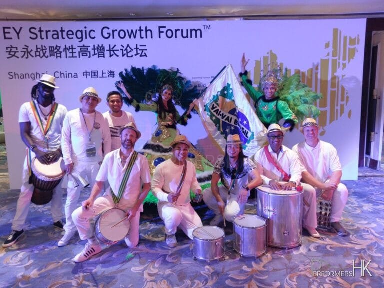 Percussion performers in white and dancers in green posing for photo