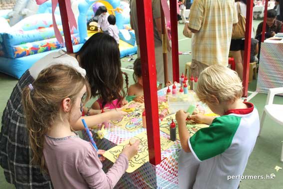 Three children in Hong Kong doing the sand art activities at a festival event.