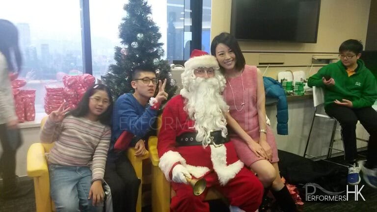 Santa with a lady and two kids taking picture in front of a Christmas tree at a HK Xmas event