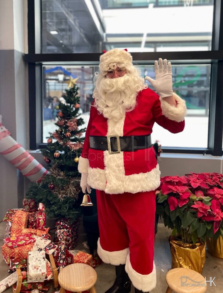 Santa in red suit in front of a christmas tree