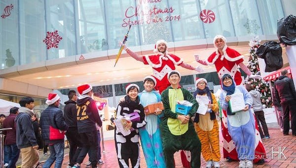 Two Xmas red and white stilt walkers standing behind a group of animal costume models