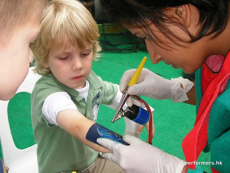 The Temporary tattoo artist in Hong Kong spraying a tattoo on a child arm