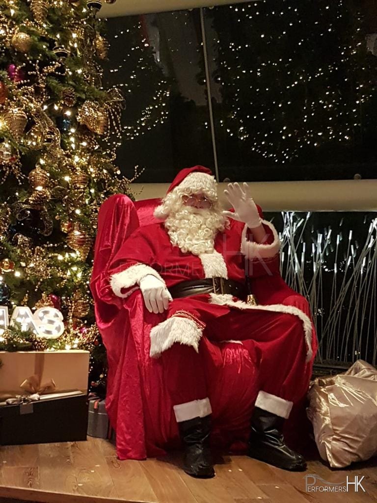 Santa in red costume sitting at the condo The Lily in repluse bay hong kong on a chair in front of a christman tree