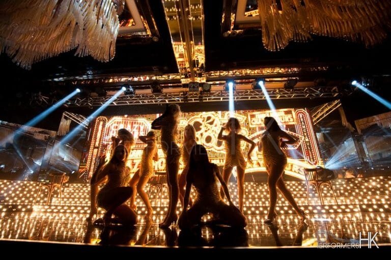 dancers on stage with gold background for crazy horse them event