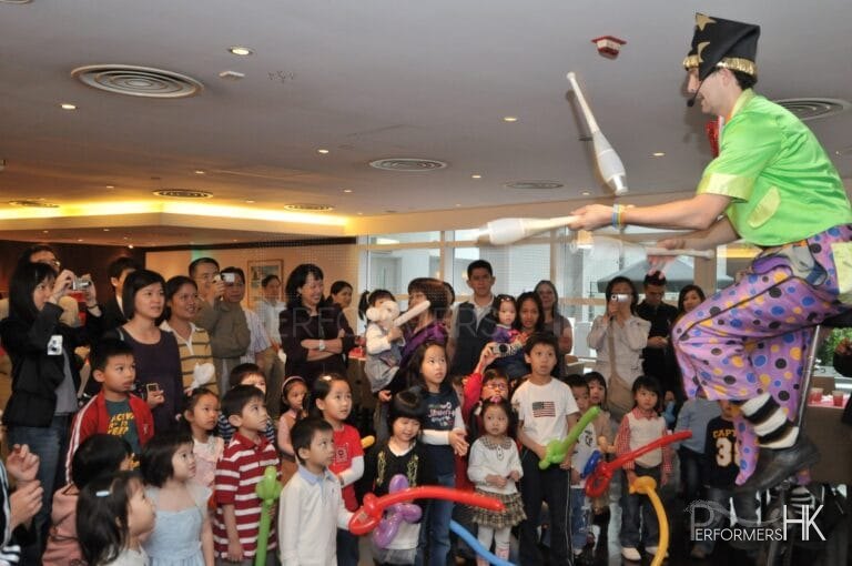 Juggler in HK performing unicycle with 3 cups at a Children event