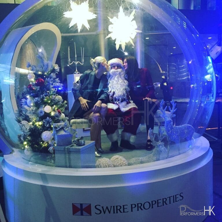 Two girls kissing santa inside a giant snow globe