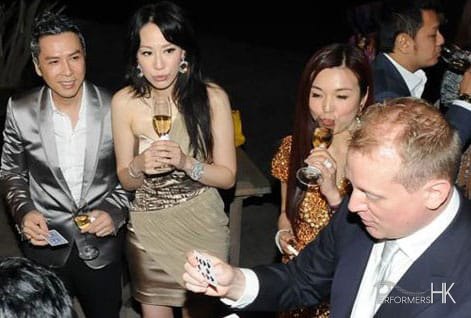 Magician performing table magic in front of the famous Hong Kong Kung Fu movie star and his model wife at a cocktails party