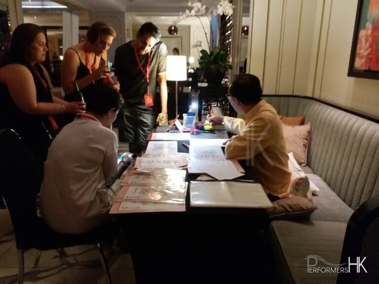 artist in hong kong doing calligraphy work foreign guests visiting from overseas looking on with interest